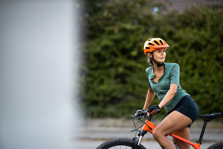 Pretty, young woman with her mountain bike going for a ride past the city limits, getting the daily cardio doseの写真素材