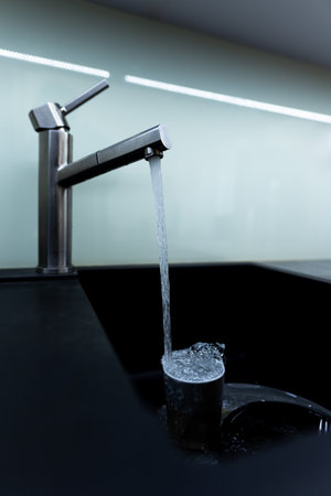 Kitchen sink with dishes and water runningの写真素材
