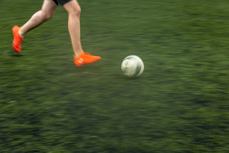 Fast moving feet of a soccer player on a pitch during a match (panned image with motion blur)の写真素材