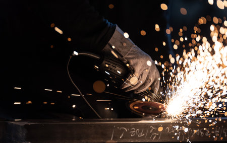Man working on iron with grinder. Man at work. Sparkles and fire from grinder cutting. Grinder. Worker.の写真素材