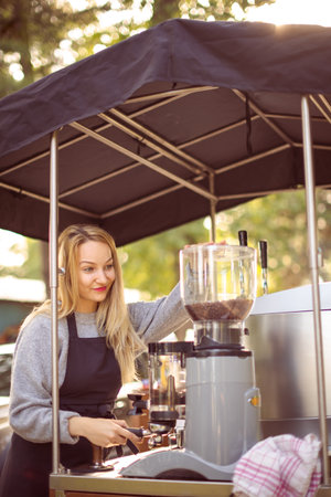 Female barrista making coffee for clients in a mobile coffee stand outdoors in a cityの写真素材