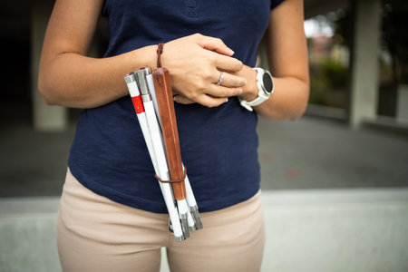 Blind woman walking on city streets, using her white cane to navigate the urban space better and to get to her destination safelyの写真素材