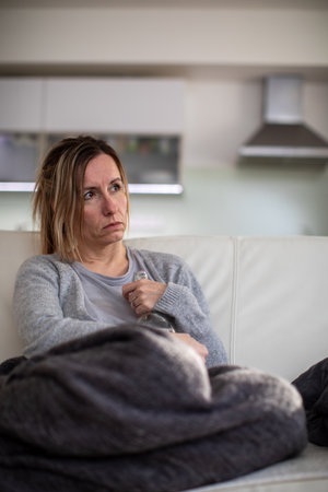 Middle aged woman at home with a bottle of strong alcohol in her hands, dealing with depression, pain, lonelinessの写真素材
