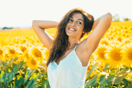 A smiling model sunbathes in a beautiful sunflower field after the pandemic ends. Perfect for summer campaignの写真素材