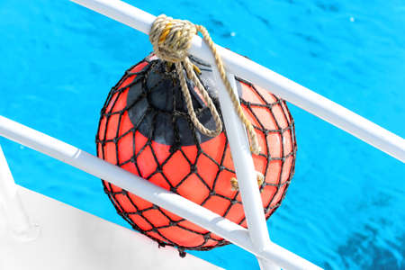 A red pear fender for a boat in a crystal clear turquoise sea during a summer excursion in Egypt