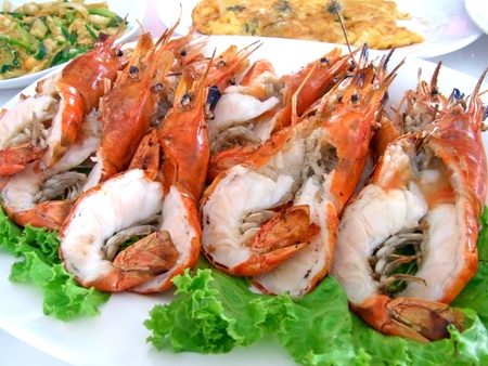 a plate full of grilled river prawn with other food in the backgroud                                   の写真素材