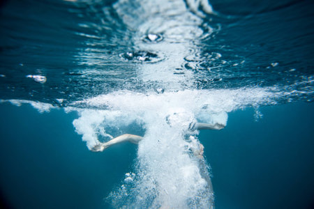 men jump into splashing blue water with bubblesの写真素材