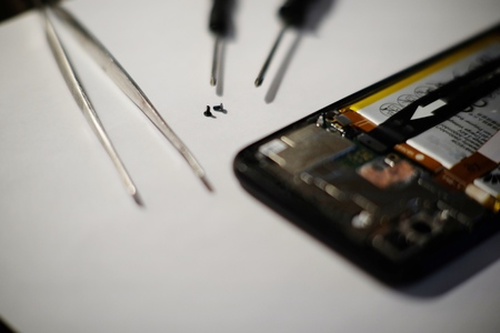 Smart phone broken and cracked screwdriver and tweezers prepairing to repair on white backgroundの写真素材
