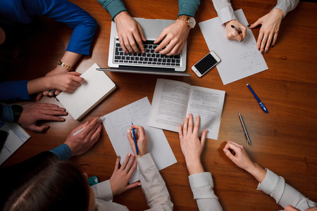 Group of People Planning, Discussing Meeting in a business office, they are reading, writing, typing. top viewの写真素材