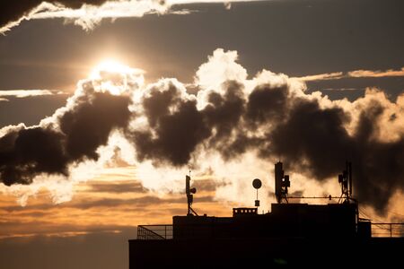 Steam rises from a smokestack on a radiorelay station silhouetted against the sunlight.の写真素材