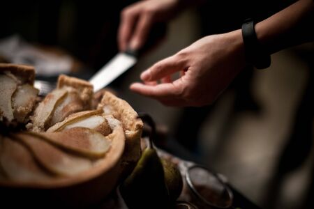 Fruit pie crust. Chefs hand cut with knife pie crust sliced on a rustic kitchen table.の写真素材