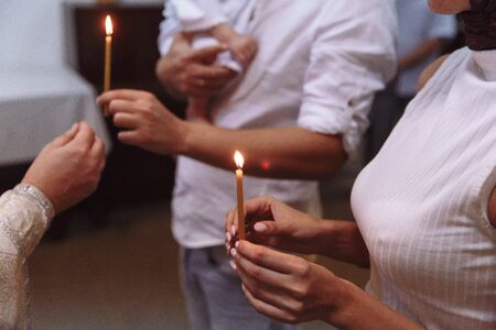 view of women and a man, holding in hands candles and a baby during the Epiphany in russian orthodox churchの写真素材