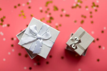 White textured gift boxes with ribbon bows surrounded by stars and snowflakes on a coral background, from above..の写真素材