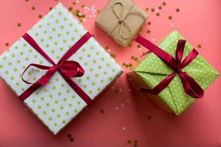 Colorful textured gift boxes with ribbon bows surrounded by stars and snowflakes on a coral background, from above..の写真素材