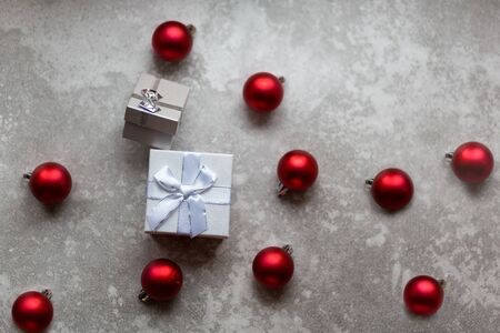 White gift box with white ribbon bow and vinous christmas balls around, isolated on gray background..の写真素材