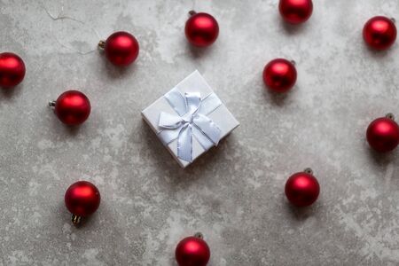 White gift box with white ribbon bow and vinous christmas balls around, isolated on gray background..の写真素材