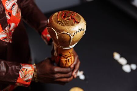 Hands of an African man in national clothes holds djembe drum surrounded by seashells..の写真素材