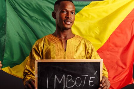 African man in a national clothes of Kongo holding a small blackboard with Hello word on his native...