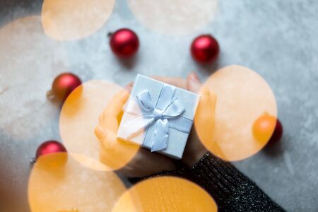 A gift in the hands from above surrounded by Christmas toys view through garland flareの写真素材