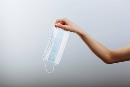 A women's hand holds a medical masks isolated in white background.の写真素材