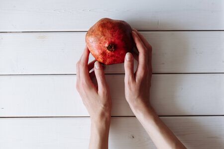 hand holding pomegranate on the white wooden table.の写真素材