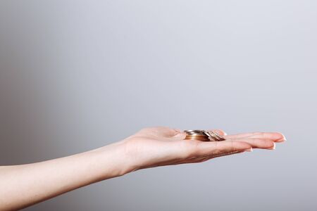 woman's hand holding coins isolated on gray background. Concept crisis, save money.の写真素材