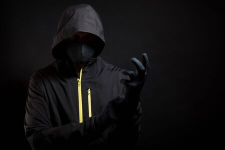 The criminal in the mask puts on a glove. Preparation for robbery.の写真素材