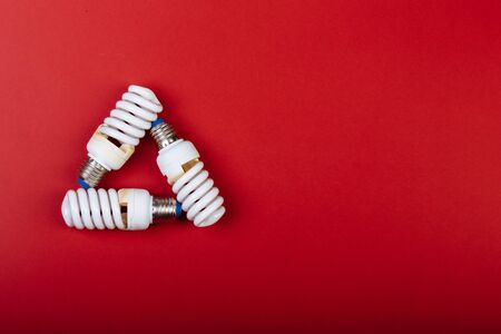 Three Energy saving lamp in shape of recycling sign isolated on red. Caption for the text.の写真素材