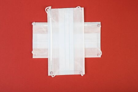 healthcare, medicine and charity concept: cross made from two white surgical masks for protection from COVID-19. Looks like a Flag of Switzerland.の写真素材