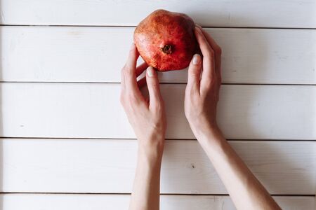 hand holding pomegranate on the white wooden table.の写真素材