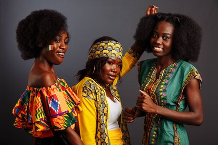Three young beautiful African fashion models have fun and laughing in traditional dress. Women from the Congo Republic, Ivory Coast, and Zimbabweの写真素材