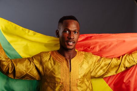 happiness african man in traditional clothes dancing with flag of Congo, isolated on gray backgroundの写真素材