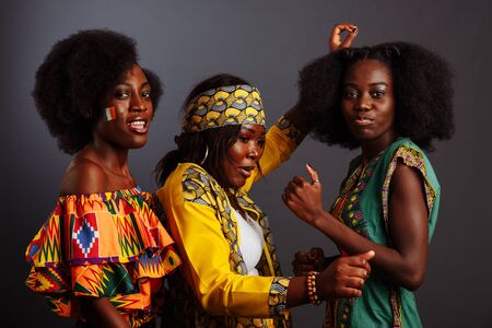 Three young beautiful African fashion models have fun and laughing in traditional dress. Women from the Congo Republic, Ivory Coast, and Zimbabweの写真素材