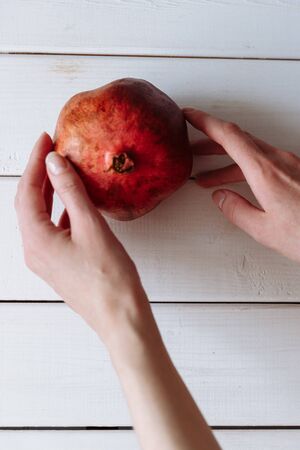 hand holding pomegranate on the white wooden table.の写真素材