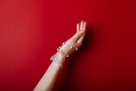 Fashion art hand woman in the glove protection against COVID-19 with Jewelry isolated on red background.の写真素材