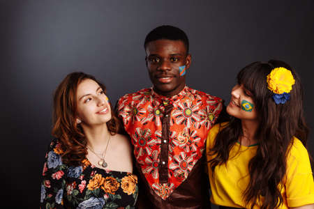 Concept of friendship and peace between countries: African man and two Latin ladies in national clothes show hug together with body arts flags Congo, Brazil, Ecuadorの写真素材