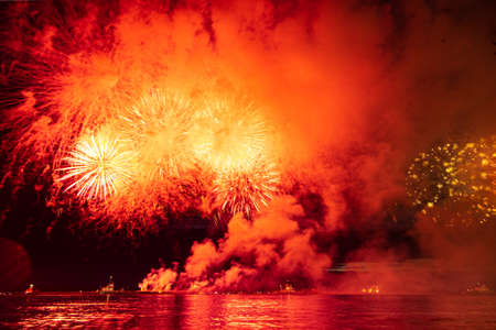 Holiday fireworks above water with reflection in the water in front of the black sky background.の写真素材