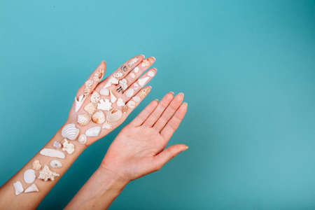 two hands: one without any shell another holds various shape sea shells.の写真素材