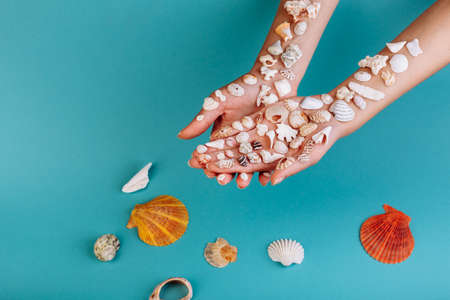 Macro of hand holding different kinds of seashells, corals in front of a blue background, isolated with a caption for text. Vacation conceptの写真素材