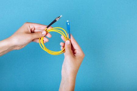 womans hands hold SC and FC connector fiber optic patch cord single mode on blue background
