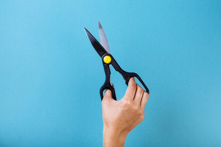 Woman hand with scissors. Isolated on blueの写真素材