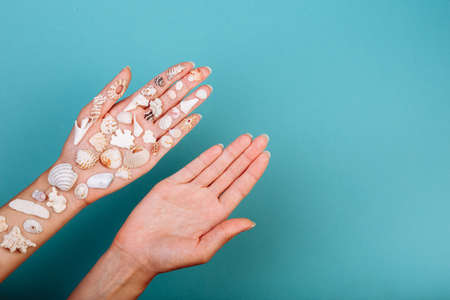 two hands: one without any shell another holds various shape sea shellsの写真素材