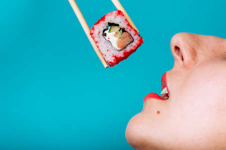 Close up macro of lips with Sushi roll. Lady eating japanese foodの写真素材