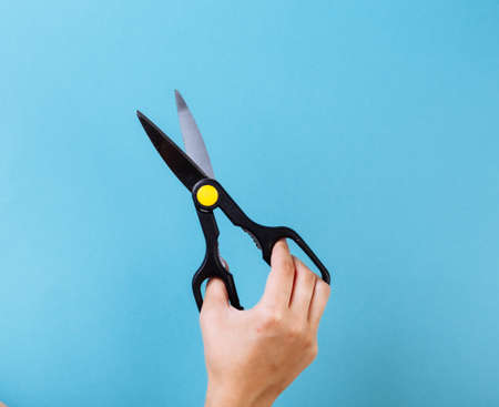 Woman hand with scissors. Isolated on blueの写真素材