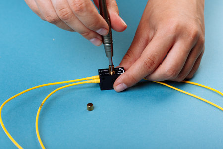 Hands tuning the Variable optic attenuator with a screwdriver. Selective focus. Blue backgroundの写真素材