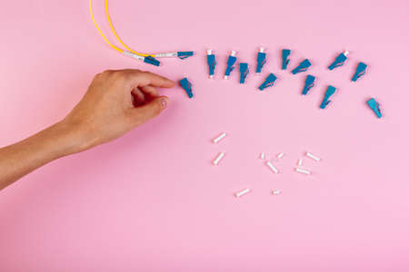 Hand takes blue LC optical attenuator on pink backgroundの写真素材