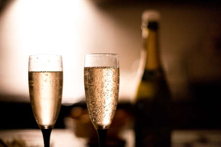 Two elegant champagne glasses on a dark surface on the kitchen.の写真素材