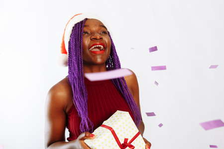 Beautiful happy woman with gift box at celebration party with confetti falling everywhere on her. Birthday or New Year eve celebrating conceptの写真素材