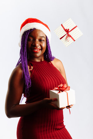 Beautiful Afro American woman is catching falling presents, looking at camera and smiling, isolated on white backgroundの写真素材