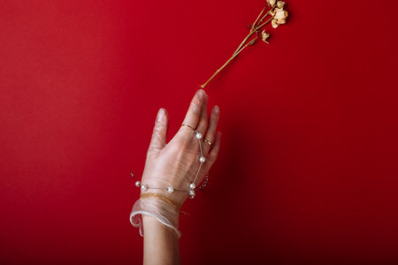 Fashion art hand woman in the glove with Jewelry in summer time and flowers behind her hand with bright contrasting makeup. Creative beauty photo hand skincare.の写真素材